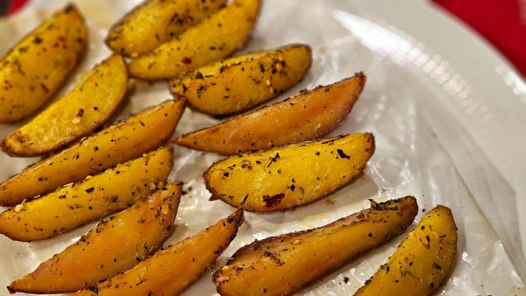 Close-up of deliciously seasoned potato wedges on parchment paper.